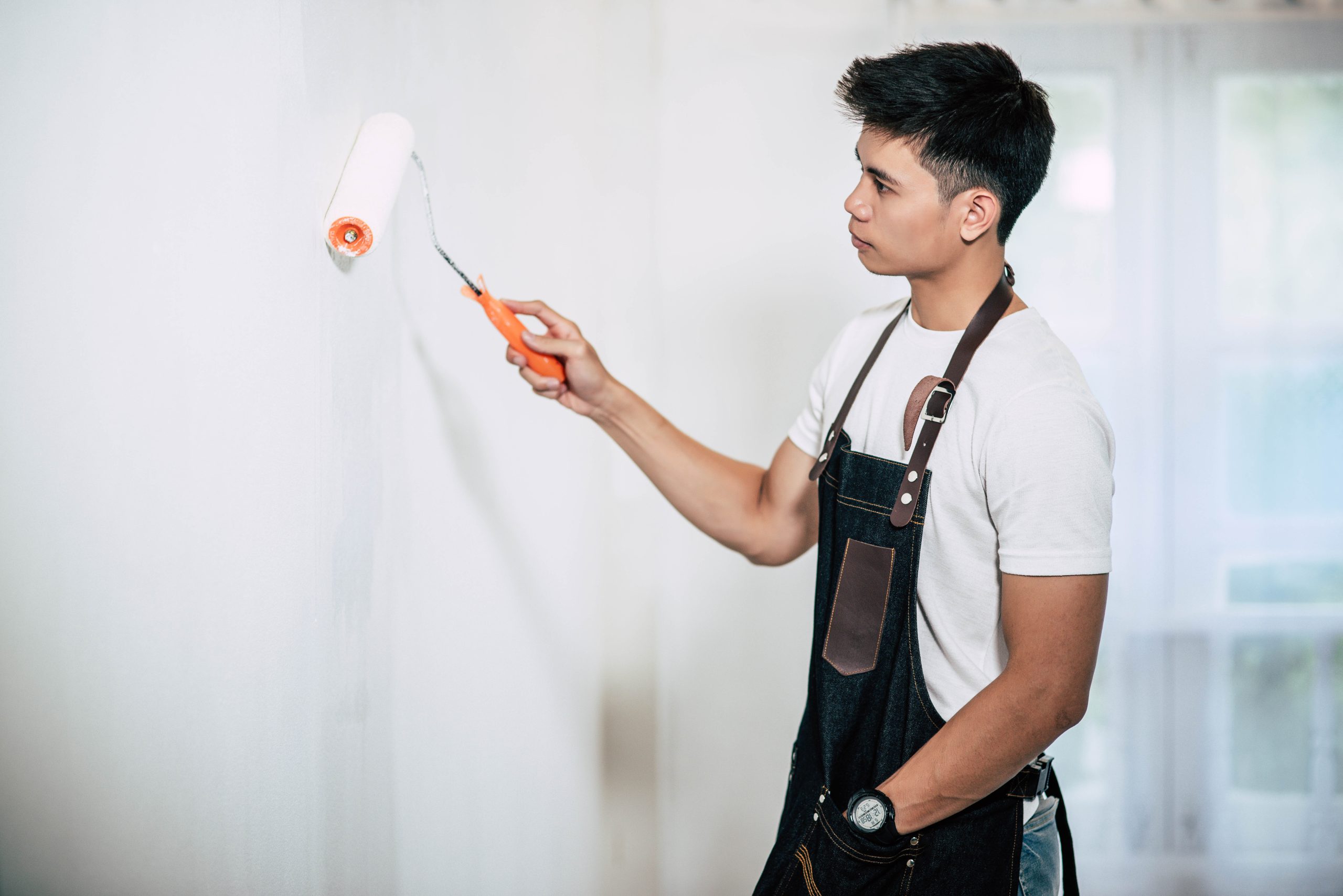 A carpenter holds a paintbrush and paints wood. priming and painting
