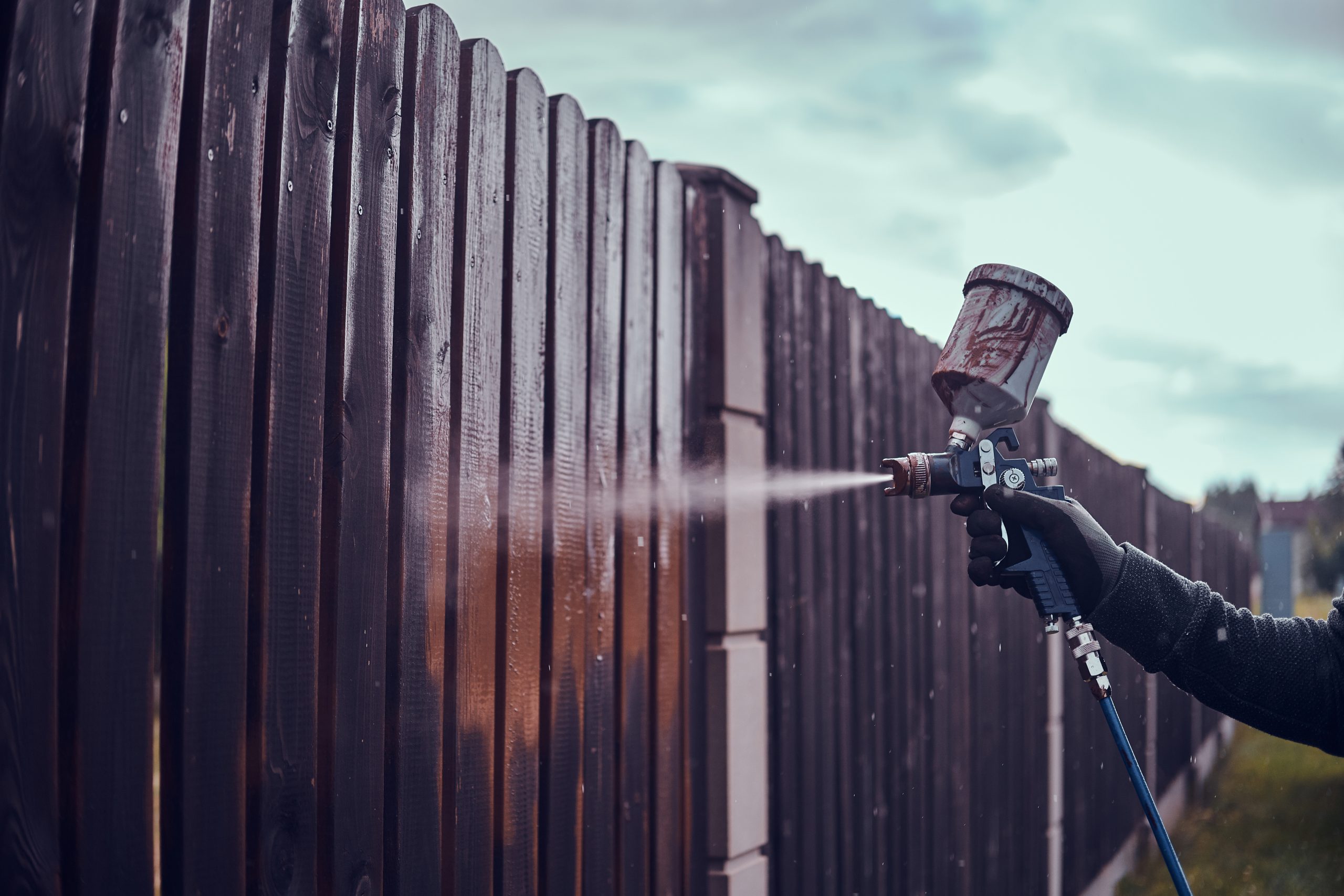 Diligent working is applying colour to the fence with airbrush fence premium paint